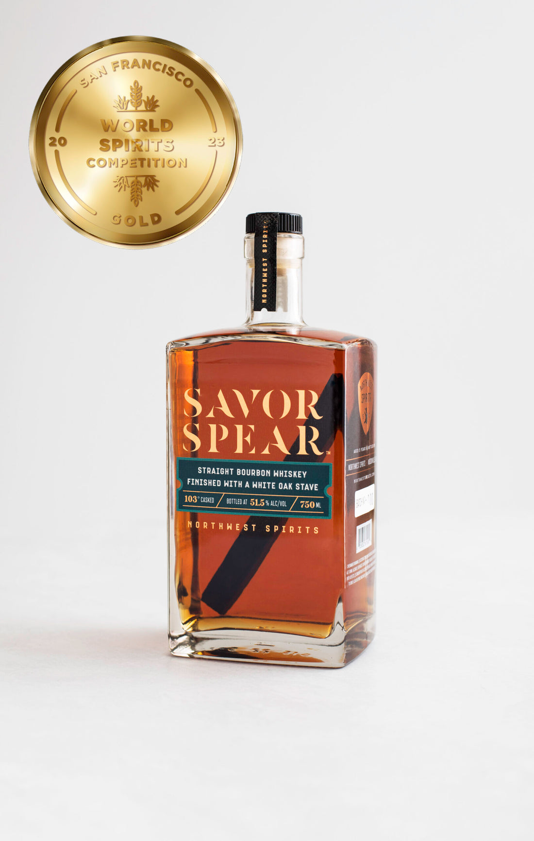Image of a bottle of Savor Spear Bourbon Whiskey sitting on a clean white backdrop. The whiskey has an oak spear inside. There is a gold medal icon to the left of the bottle indicating the award that was won.