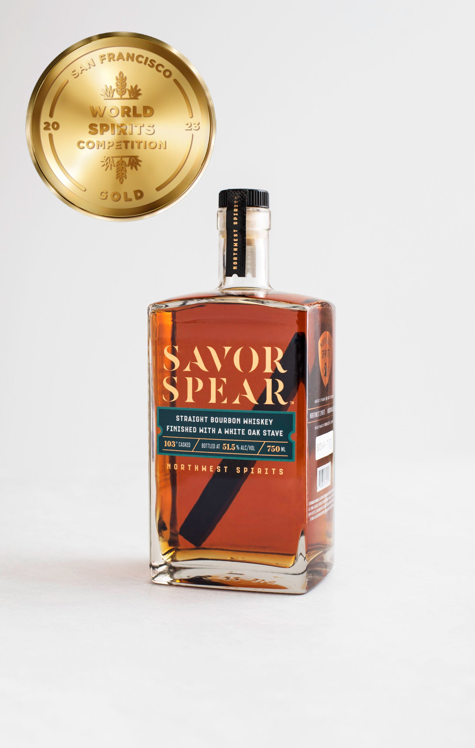 Image of a bottle of Savor Spear Bourbon Whiskey sitting on a clean white backdrop. The whiskey has an oak spear inside. There is a gold medal icon to the left of the bottle indicating the award that was won.