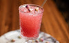 Pink cocktail with decorative elements in a textured glass on a wooden surface