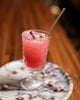Pink cocktail with decorative elements in a glass on a marble coaster.