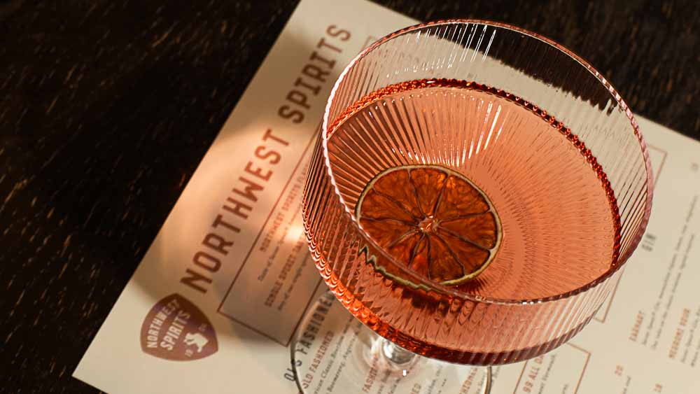 Cocktail glass with a dried orange slice on a Northwest Spirits menu
