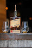 Savor Spear Whiskey bottle with two glasses on a rustic surface