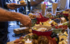 Table with various food items and people around it