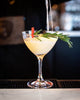 Rosemary Lemon Enchantress Cocktail with a sprig of rosemary on a bar counter