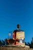 Bottle of Savor Spear whiskey with a glass of whiskey against a blue sky background