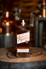 Bottle of Savor Spear whiskey on a wooden barrel with a blurred bar background