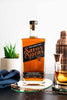 Bottle of Savor Spear whiskey on a table with a glass and cocktail shaker in the background.