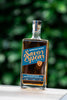 Bottle of Savor Spear whiskey with a blurred green background