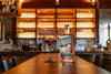 Bottle of Savor Spear whiskey on a bar counter with a cocktail glass in a bar setting.