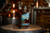 Savor Spear whiskey bottle on a wooden barrel with a blurred bar background