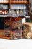 Three bottles of Savor Spear whiskey on a bar counter with a blurred bar background.