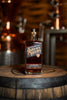 Bottle of Savor Spear whiskey on a wooden barrel with a blurred bar background