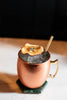 Copper mug with a cocktail and a dried fruit garnish on a marble surface